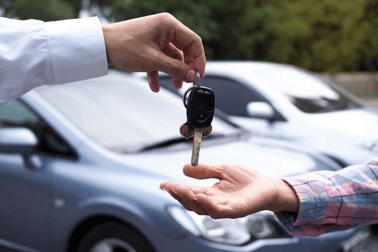 Close-up of a car dealer giving client car keys